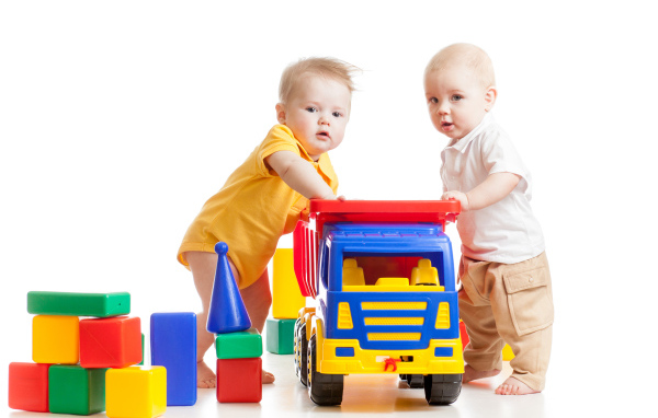 Два маленьких ребенка с игрушками на белом фоне