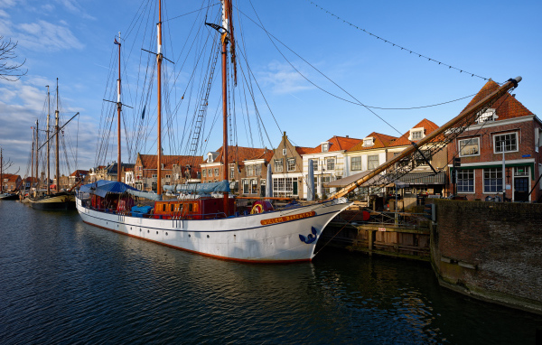 Парусное судно Willem Barentsz с опущенными парусами на причале у домов