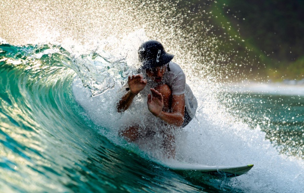 Парень серфингист ловит голубую морскую волну