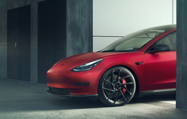 Красный автомобиль Tesla Model 3 2019 года выезжает в гаража