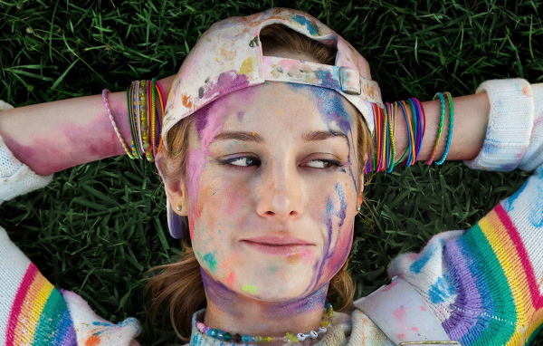 Актриса Бри Ларсон с лицом в краске лежит на траве