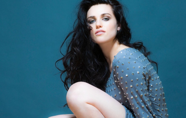 Актриса Кэти Макграт в сером платье на синем фоне