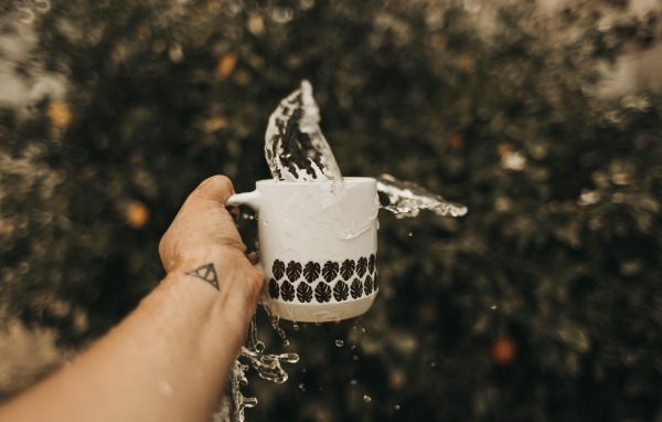 Чашка с водой в руке с татуировкой 