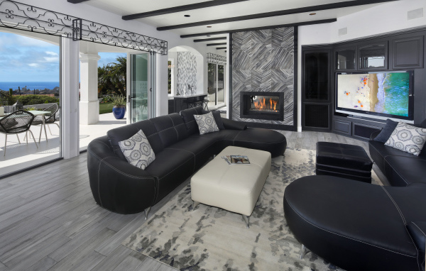 Large spacious living room with black leather sofas, TV and fireplace.