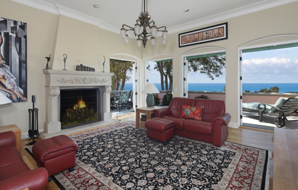 Гостиная с кожаным диваном, большими окнами и камином 