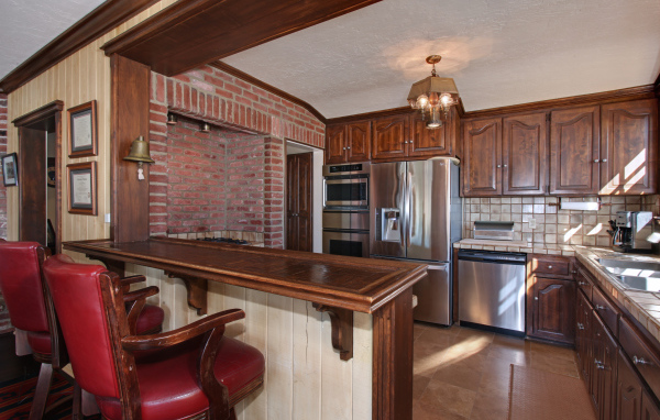 Просторная кухня с деревянной мебелью и кожаными стульями