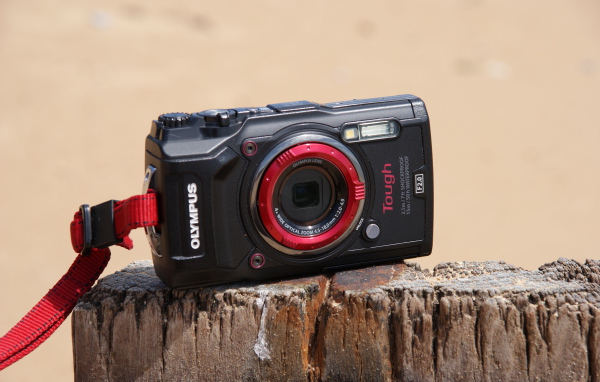 Стильный фотоаппарат Olympus Tough TG-5 стоит на пне