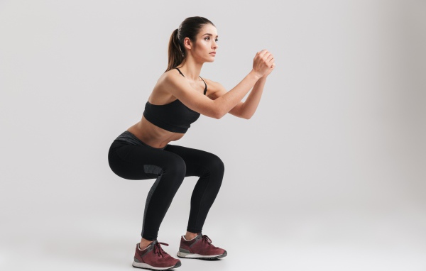 Девушка занимается гимнастикой на сером фоне