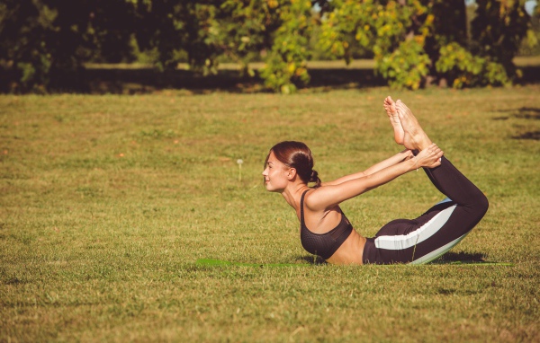 Девушка занимается гимнастикой на зеленой траве