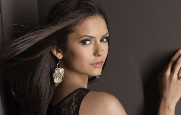 Ветер развивает волосы актрисы Нина Добрев на фоне стены