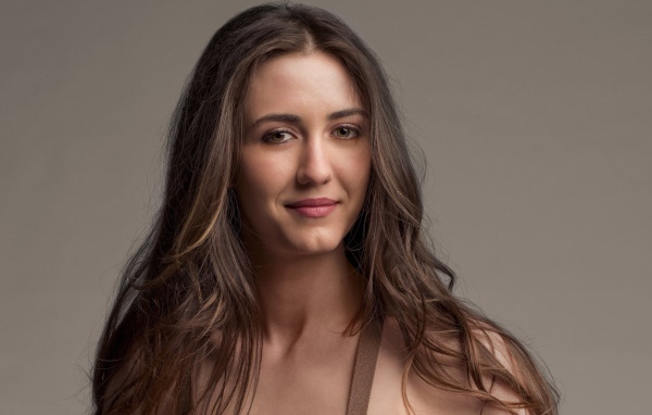 Молодая длинноволосая девушка, актриса Мэйделин Зима на сером фоне