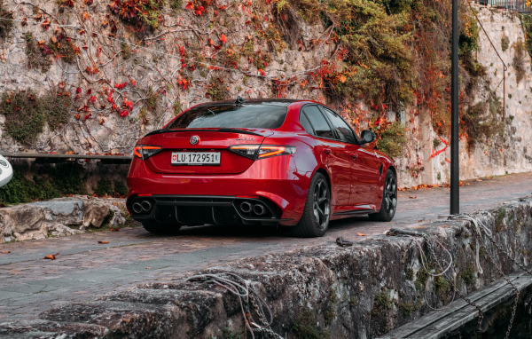 Красный автомобиль Alfa Romeo Giulia Quadrifoglio 2021  года на дороге в горах