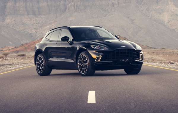 Черный автомобиль aston Martin DBX 2020 года на трассе в горах
