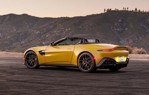 Желтый автомобиль  Aston Martin Vantage Roadster, 2021 года на фоне гор 