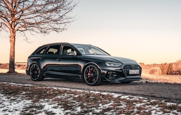 Черный автомобиль  Audi RS 4 Avant 2020 года на дороге у дерева