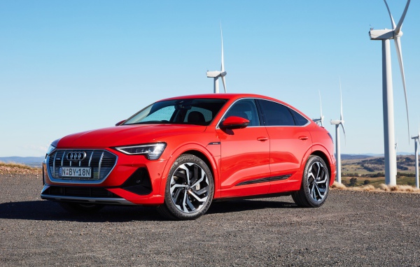 Красный автомобиль Audi E-Tron 50 Quattro Sportback S Line 2020 на фоне ветряных турбин
