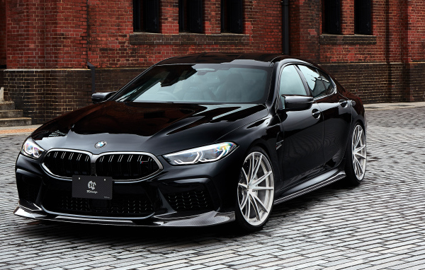 Дорогой черный автомобиль BMW M8 у стены