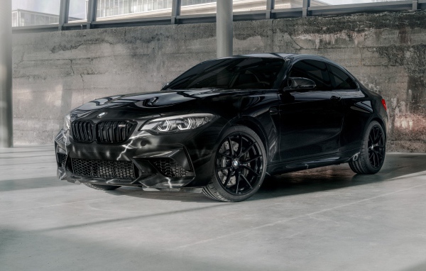 Черный автомобиль  BMW M2, 2020 года у бетонной стены