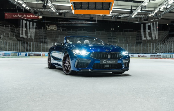 Кабриолет BMW M8,  2020 года с включенными фарами на стадионе 