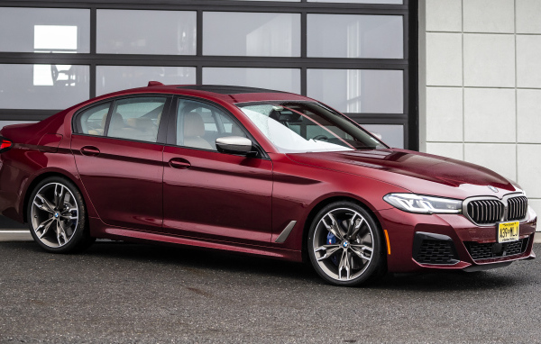 Красный автомобиль BMW M550i XDrive, 2021 года у гаража