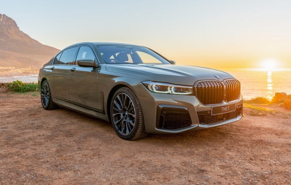 Стильный дорогой автомобиль BMW 745Le , 2020 года на фоне заката