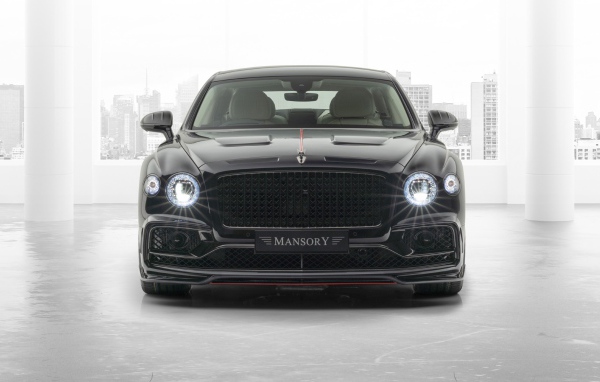 Черный автомобиль Mansory Bentley Flying Spur 2020 года с включенными фарами 