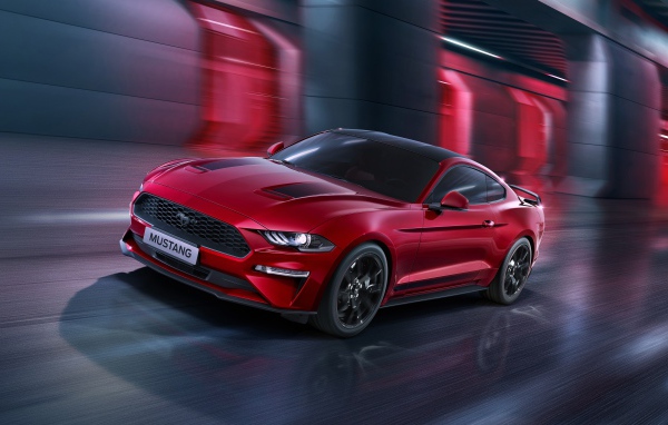 Красный автомобиль Ford Mustang едет по городу