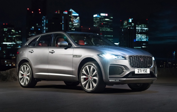 Серебристый Jaguar F-Pace R-Dynamic 2020 года на фоне ночного мегаполиса 