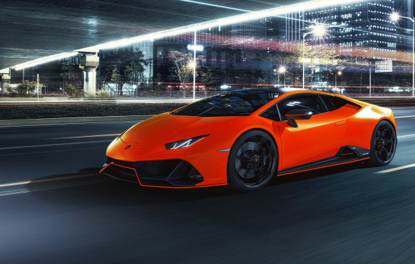 Оранжевый автомобиль Lamborghini Huracán EVO 2021 года на фоне города