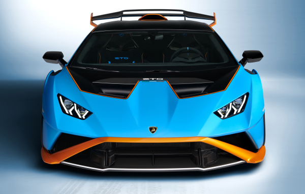 Голубой автомобиль Lamborghini Huracán STO 2021 года вид спереди на сером фоне