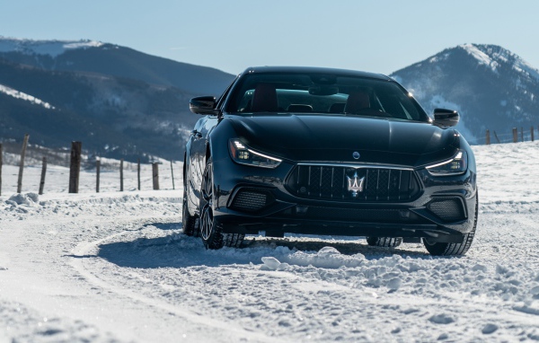 Черный автомобиль Maserati Ghibli S Q4, 2020 года едет по заснеженной дороге