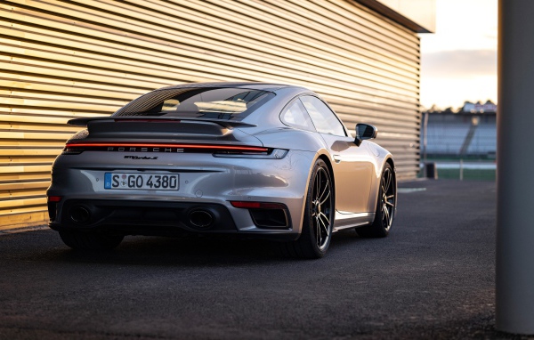 Серебристый автомобиль Porsche 911 Turbo S 2020 года у гаража