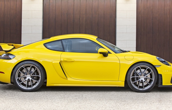 Желтый автомобиль Porsche 718 Cayman GT4 2020 года вид сбоку