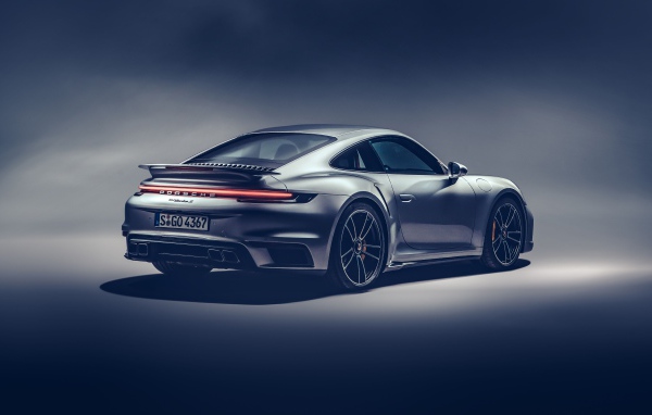 Автомобиль Porsche 911 Turbo S 2020 года на сером фоне вид сзади