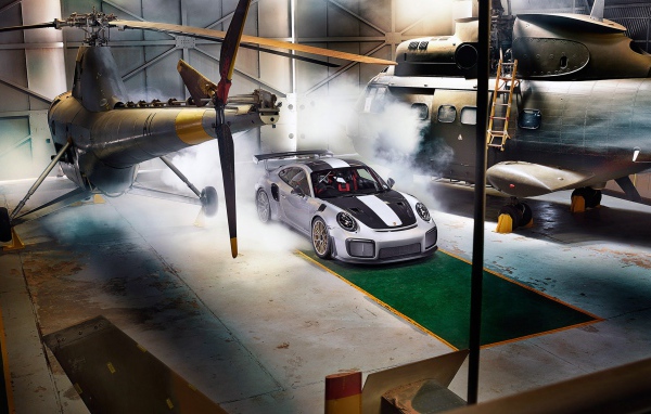 Автомобиль Porsche 911 GT2 RS в ангаре с вертолетами