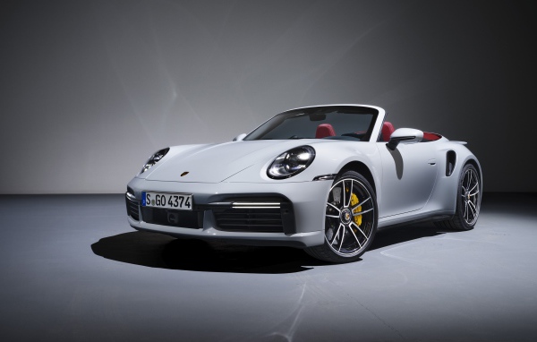 Белый кабриолет Porsche 911 Turbo S 2020 года на сером фоне
