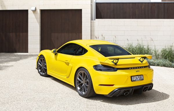 Желтый автомобиль Porsche 718 Cayman GT4, 2020 года у гаража 