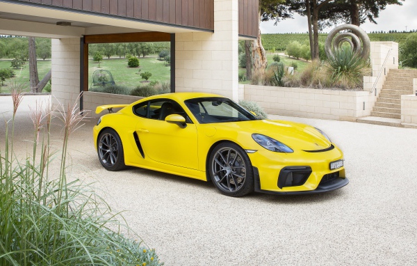 Желтый автомобиль Porsche 718 Cayman GT4, 2020 года у дома