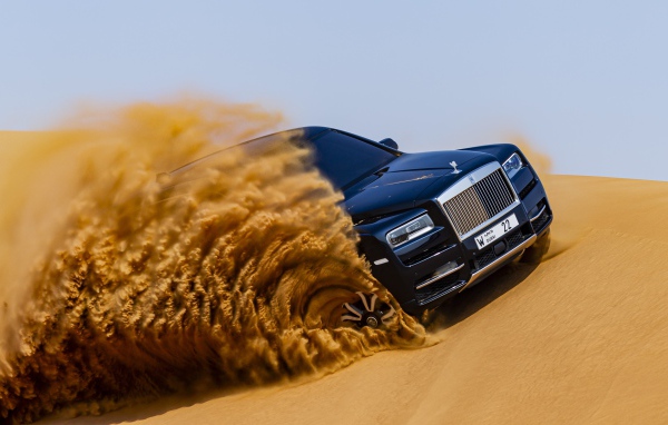 Черный Rolls-Royce Cullinan дрифтует по песку 