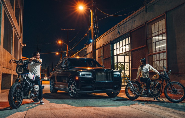 Черный стильный автомобиль Rolls-Royce Cullinan на улице города с байкерами