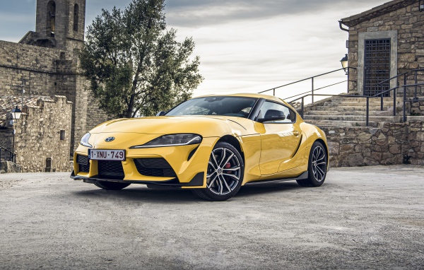 Желтый автомобиль Toyota GR Supra 2, 2020 года у старого здания 