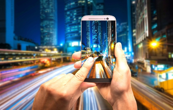 Мужчина делает фото ночного города на смартфон 