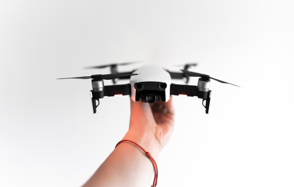 Белый квадрокоптер в руке на белом фоне
