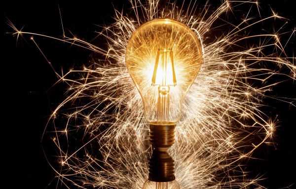 Зажженная лампа на черном фоне с искрами 