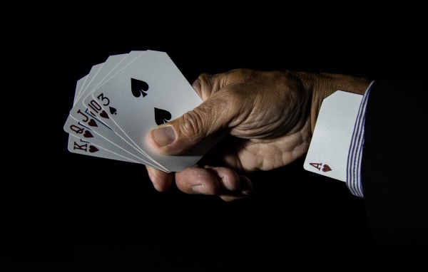 Туз в рукаве у шулера на черном фоне 