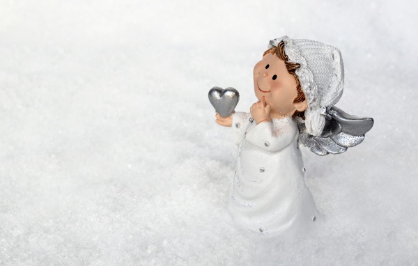 Статуэтка ангела стоит на снегу 