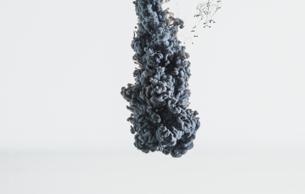 Black paint dissolves in water on a white background
