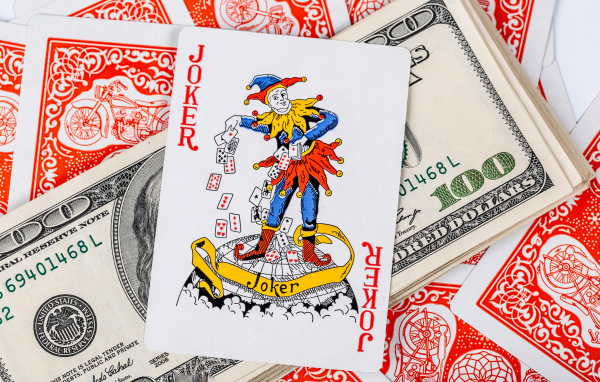 Карточный Джокер и пачка стодолларовых купюр