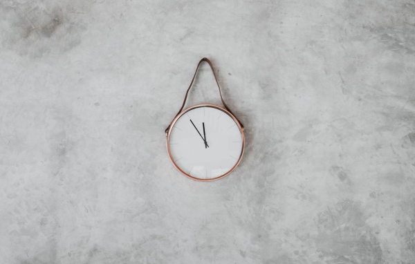 Часы с черными стрелками висят на серой стене 