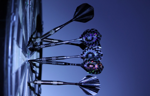 Дротики в доске для дартс на синем фоне 